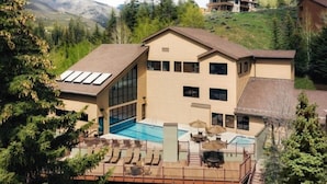 A two-story building with a large glass front, a swimming pool, and a deck with lounge chairs.
