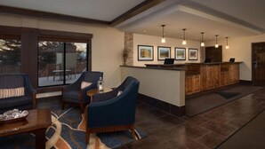 A spacious lobby with a reception desk, comfortable seating area, and large windows offering a view of the outdoors.