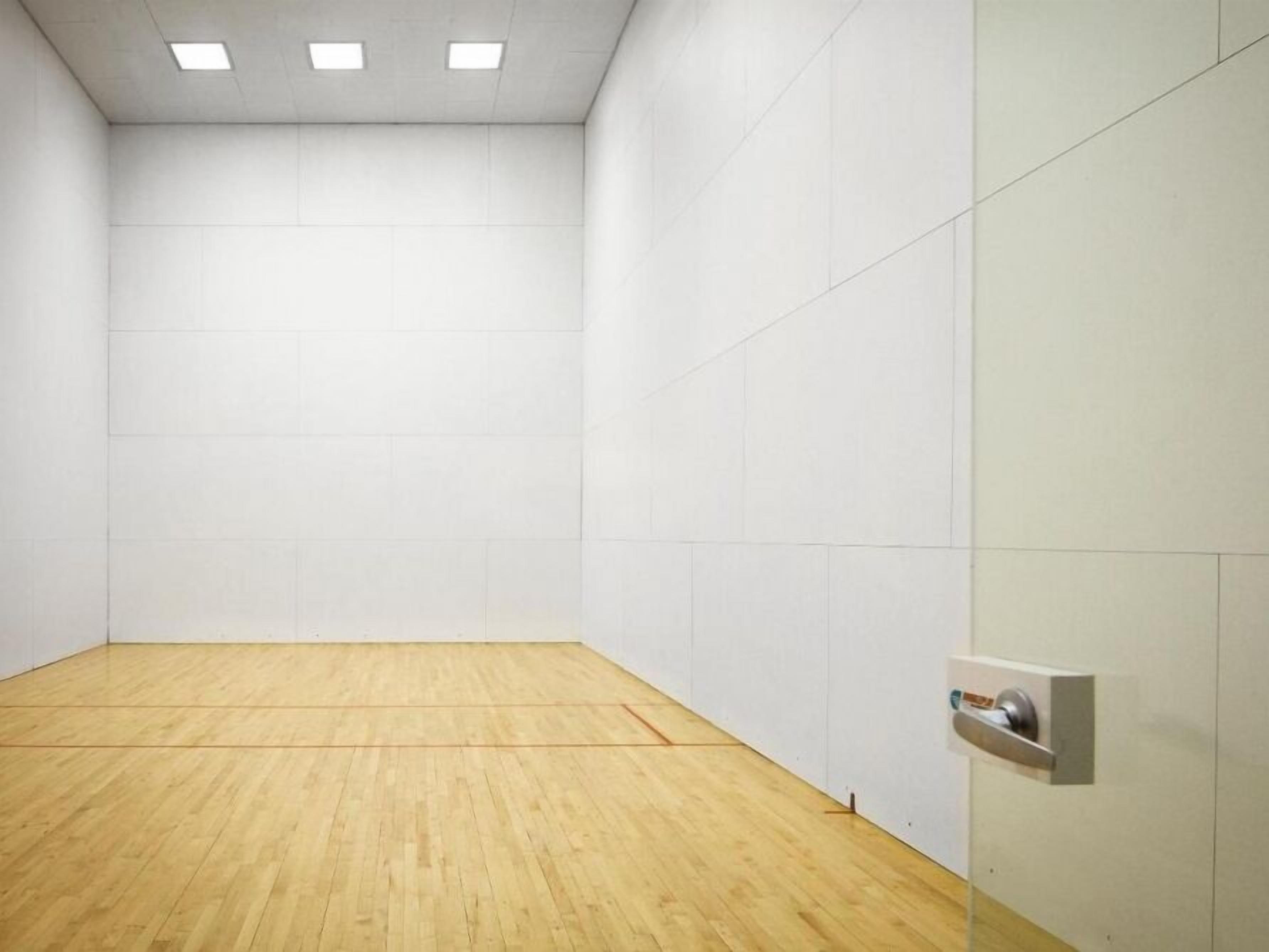 Una habitación limpia y vacía con piso de madera, paredes blancas y una puerta con picaporte.