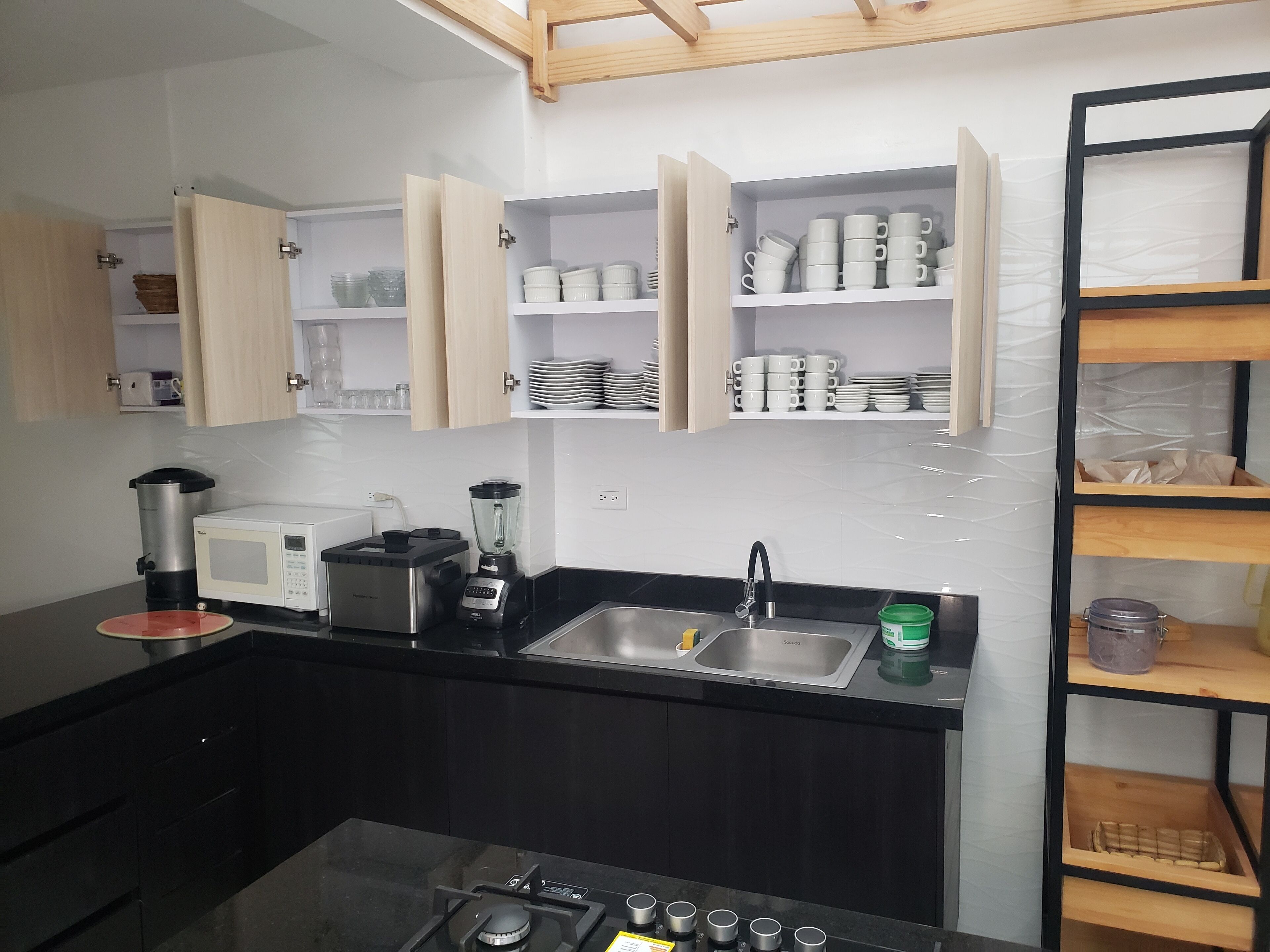 A modern kitchen with built-in cabinets, a gas stove, a microwave, a coffee maker, and a blender.
