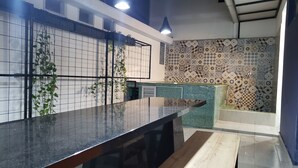 Una cocina moderna con encimera negra, salpicadero de azulejos y plantas colgantes.