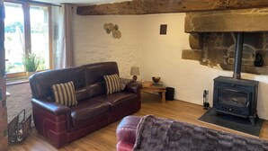 A cozy living room with a leather sofa, a fireplace, and a stone wall.