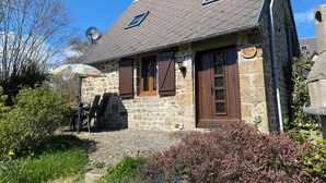 A stone house with a sloped roof, two windows, and a door.