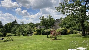 A grassy area with stone buildings, trees, and a clear sky.