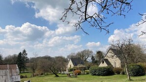 A rural setting with stone buildings, a grassy field, and a cow grazing.