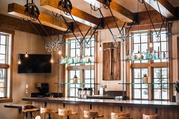Eine Bar mit Holzbalken, hängenden Lampen und Regalen mit Flaschen.