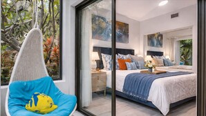 Een moderne slaapkamer met een groot bed, een hangstoel en uitzicht op de omgeving.