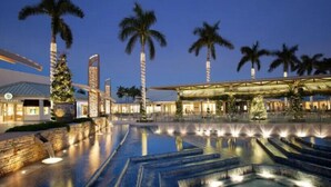 Een resort met een groot zwembad, palmbomen en moderne architectuur.
