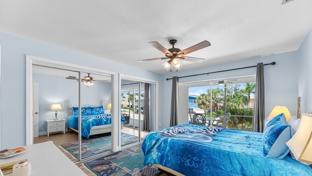 Quarto com uma cama grande, um ventilador de teto e vista para o exterior.