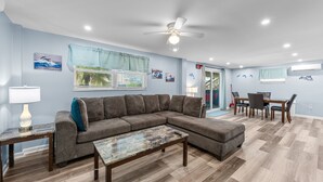A modern living room with a sectional sofa, a coffee table, and a dining area with a table and chairs.