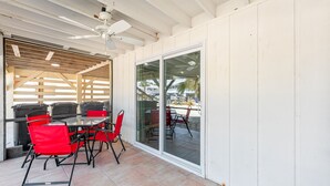 A covered patio with a table and chairs, a ceiling fan, and a sliding glass door leading to an outdoor area.