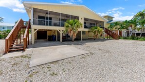 A modern building with a flat roof, large windows, and a covered outdoor area with palm trees.