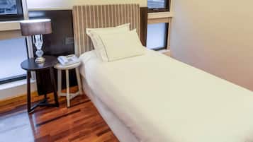 A hotel room with a bed, a bedside lamp, a nightstand, and a window.