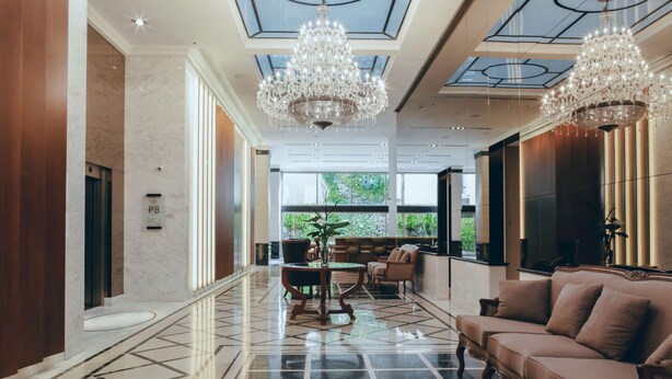 Un vestíbulo amplio con piso de mármol, un sofá, una mesa y dos candelabros.