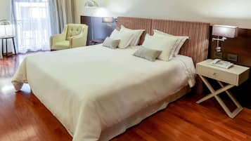 A neatly made bed with white linens, a striped headboard, and a bedside table with a lamp and phone.