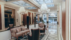 Un vestíbulo amplio con techo alto, candelabros, un mostrador de recepción y zonas de estar.