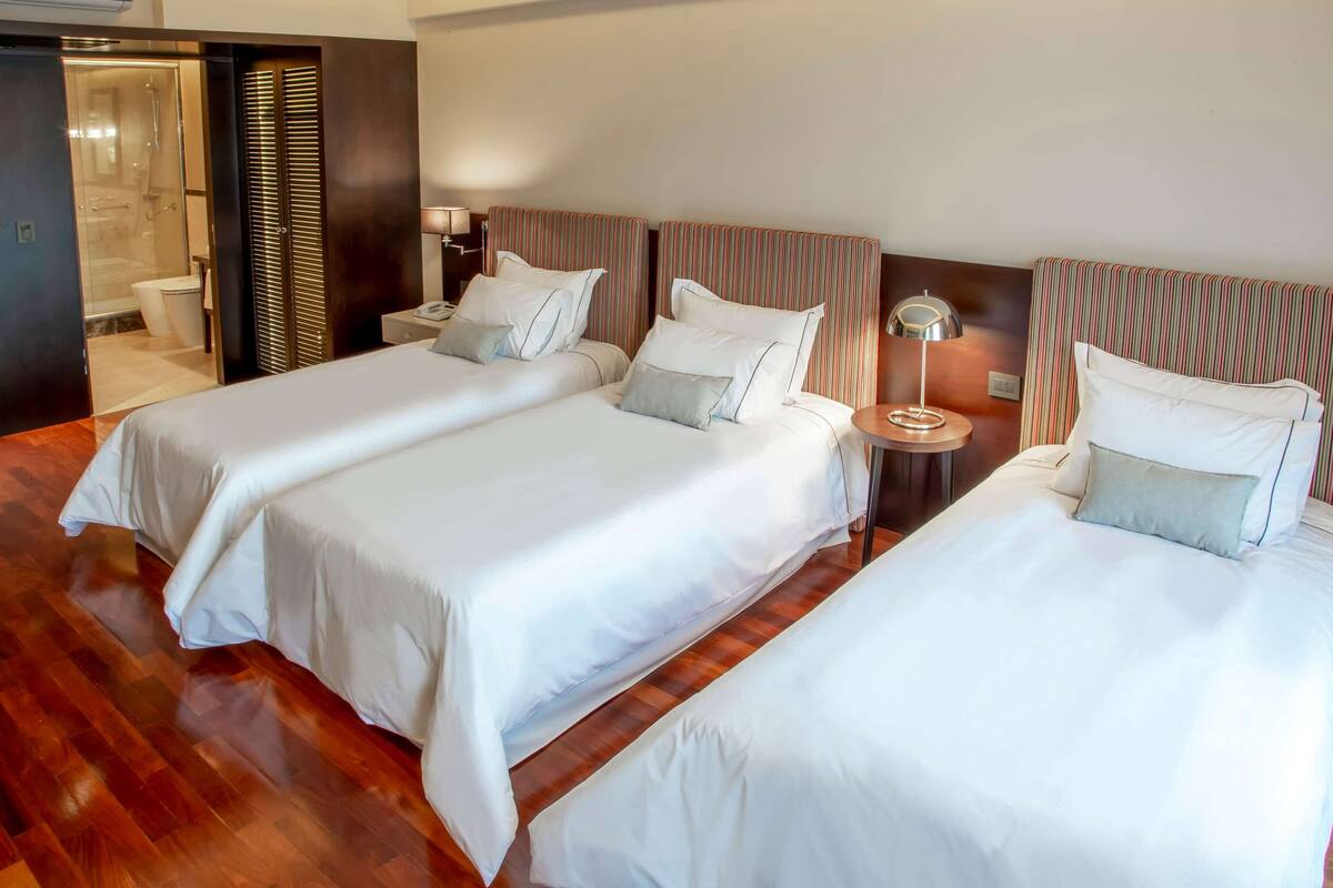 A hotel room with two beds, a bathroom, and a wooden floor.