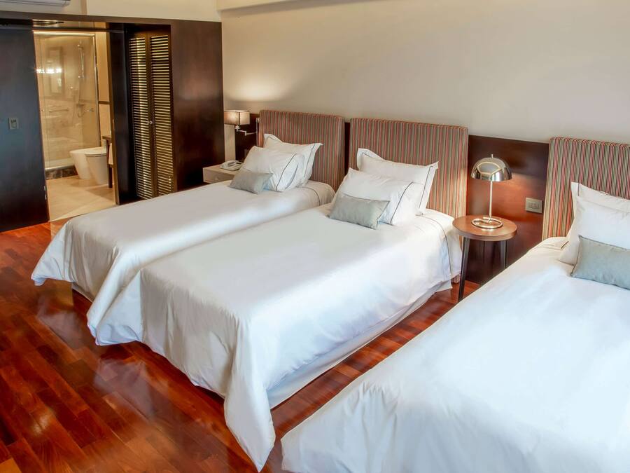 A hotel room with two beds, a bathroom, and a wooden floor.