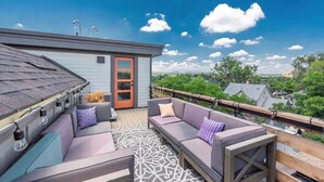 A rooftop deck with a gray building, a wooden railing, and a view of the cityscape. - Luxury Rowhome 🏔 Mountain Views Littleton Main St (Littleton)