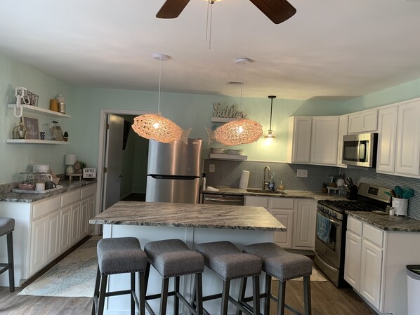 A modern kitchen with a central island, bar stools, stainless steel appliances, and decorative pendant lights. - Gem on Lake Tenkiller with open floor plan and game room for kids/adults. (Park hill)