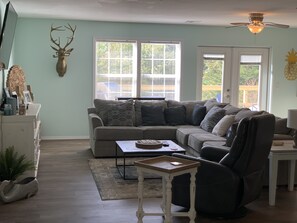 A living room with a sectional sofa, a small table, and a ceiling fan. - Gem on Lake Tenkiller with open floor plan and game room for kids/adults. (Park hill)