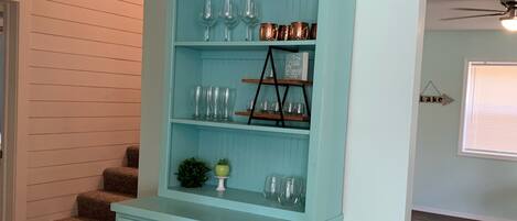 A light blue built-in shelving unit with glassware and decorative items.