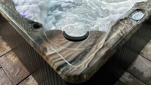 Un bain à remous doté d’un panneau de commande, entouré d’une clôture en treillis de bois.