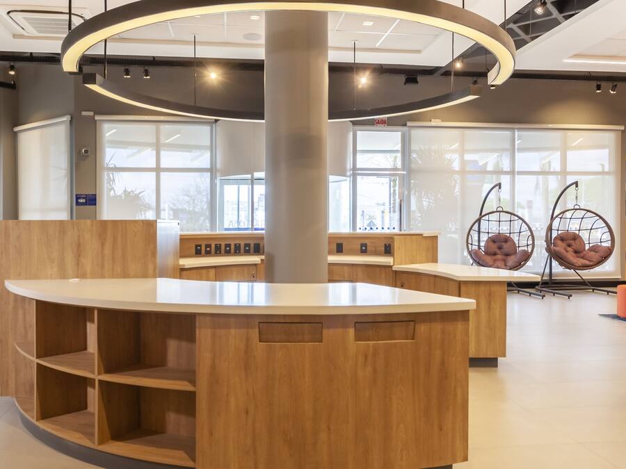 Un área de recepción moderna con un mostrador central de madera, asientos y una lámpara circular.
