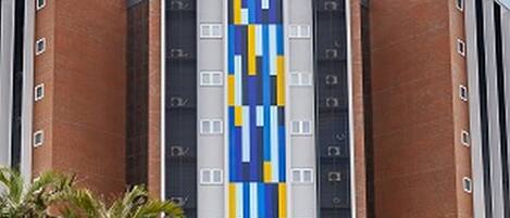 Un hotel con fachada moderna, que presenta un llamativo logo 'tru' y un diseño vertical a rayas de azul y amarillo.
