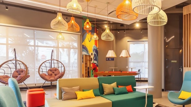 A modern lounge area with hanging pendant lights, comfortable seating, and a checkered floor pattern. - Tru By Hilton Criciúma (Criciuma)