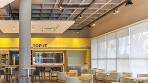 A modern breakfast area with tables and chairs, a large window, and a sign reading "TOP IT BREAKFAST". - Tru By Hilton Criciúma (Criciuma)