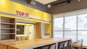 A breakfast area with a long wooden counter and several chairs. - Tru By Hilton Criciúma (Criciuma)
