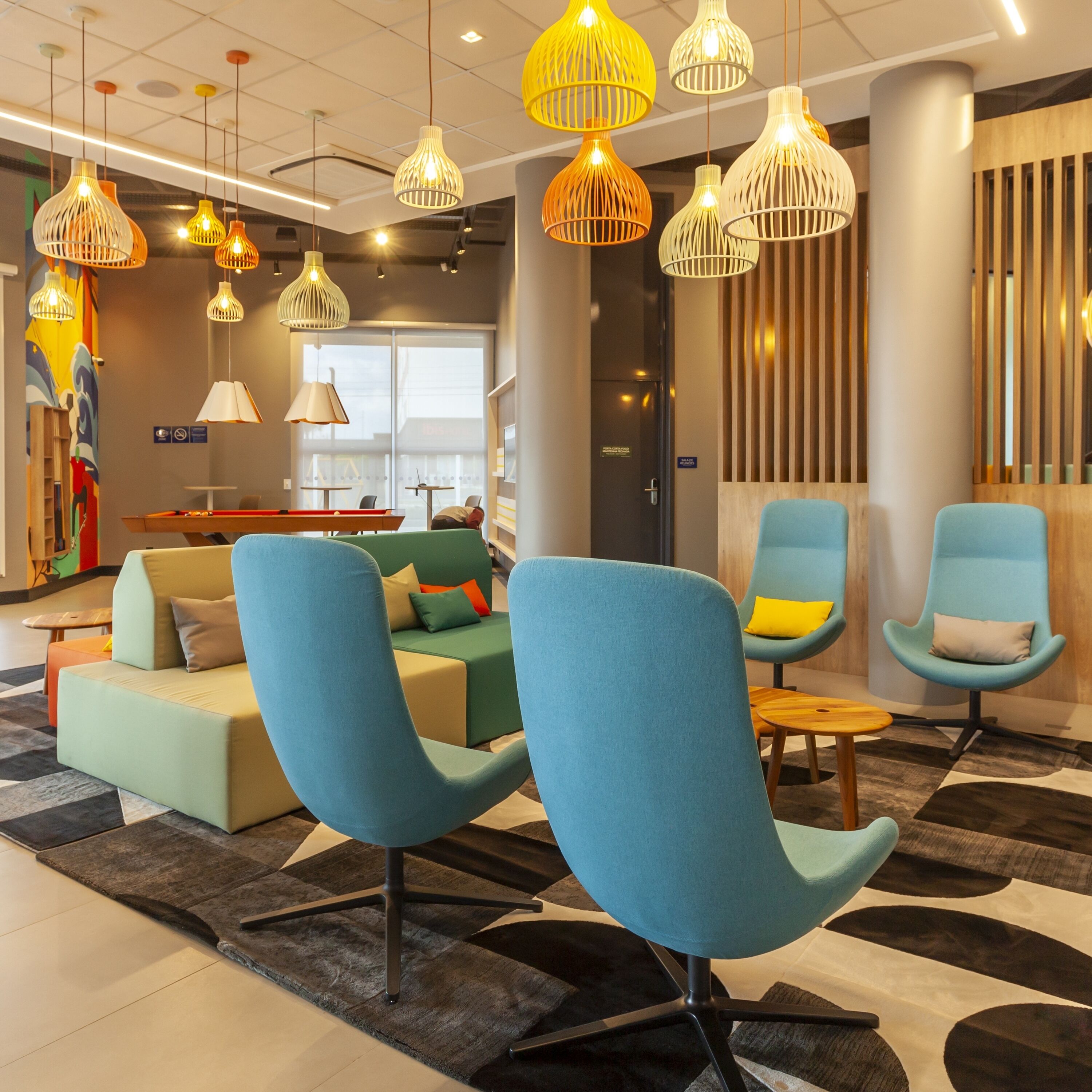 A modern lounge area with blue armchairs, a sofa, and a pool table.