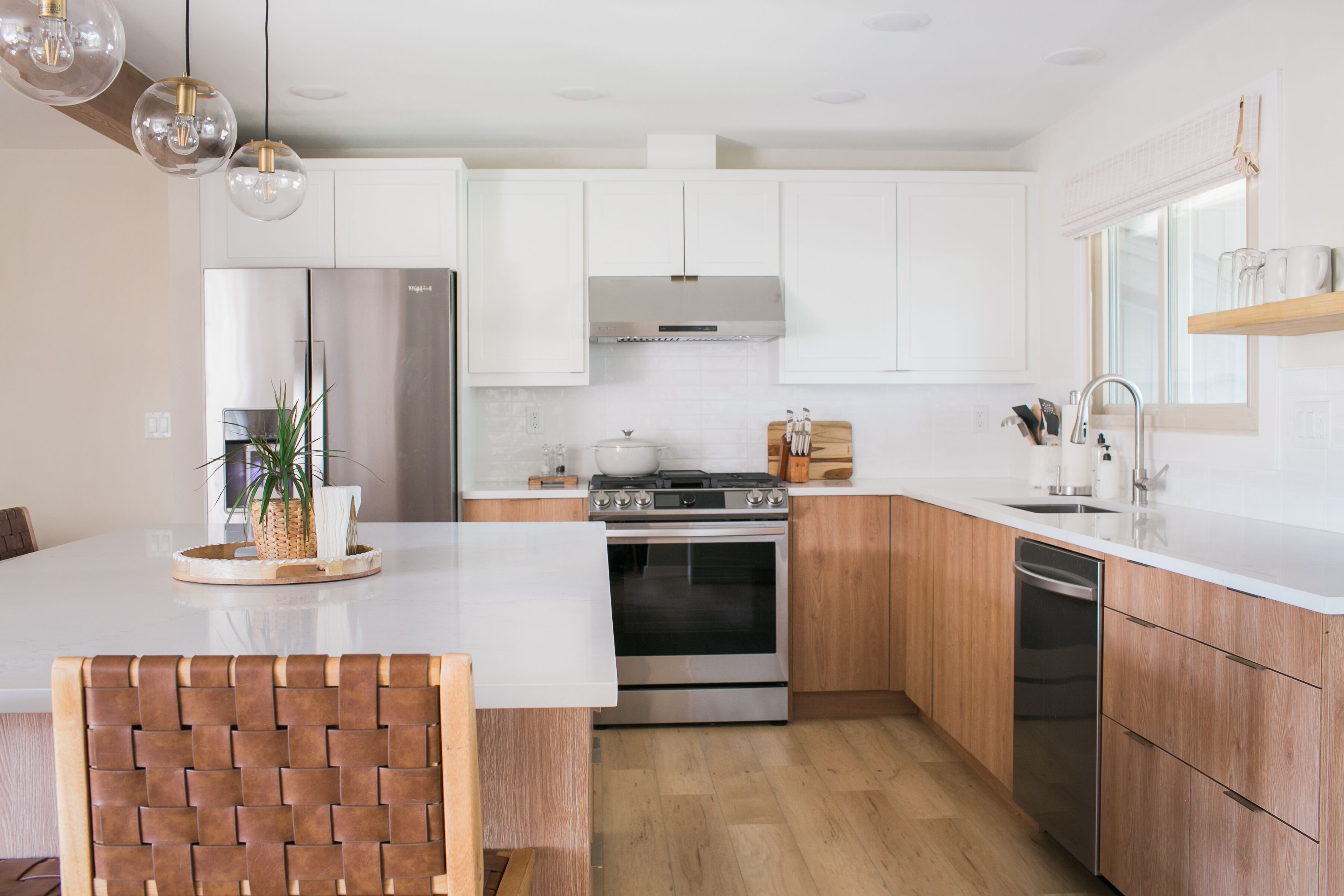 A modern kitchen with white cabinets, stainless steel appliances, and a wooden island.