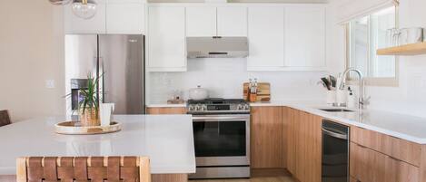 A modern kitchen with white cabinets, stainless steel appliances, and a wooden island.