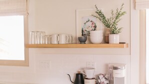 A kitchen with a wooden shelf holding mugs, a coffee maker, and a potted plant. - Beautiful Modern Home - Heated Indoor Pool (Spokane)