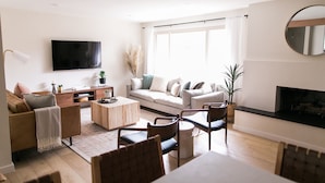A modern living room with a sofa, coffee table, chairs, a TV, and a fireplace. - Beautiful Modern Home - Heated Indoor Pool (Spokane)