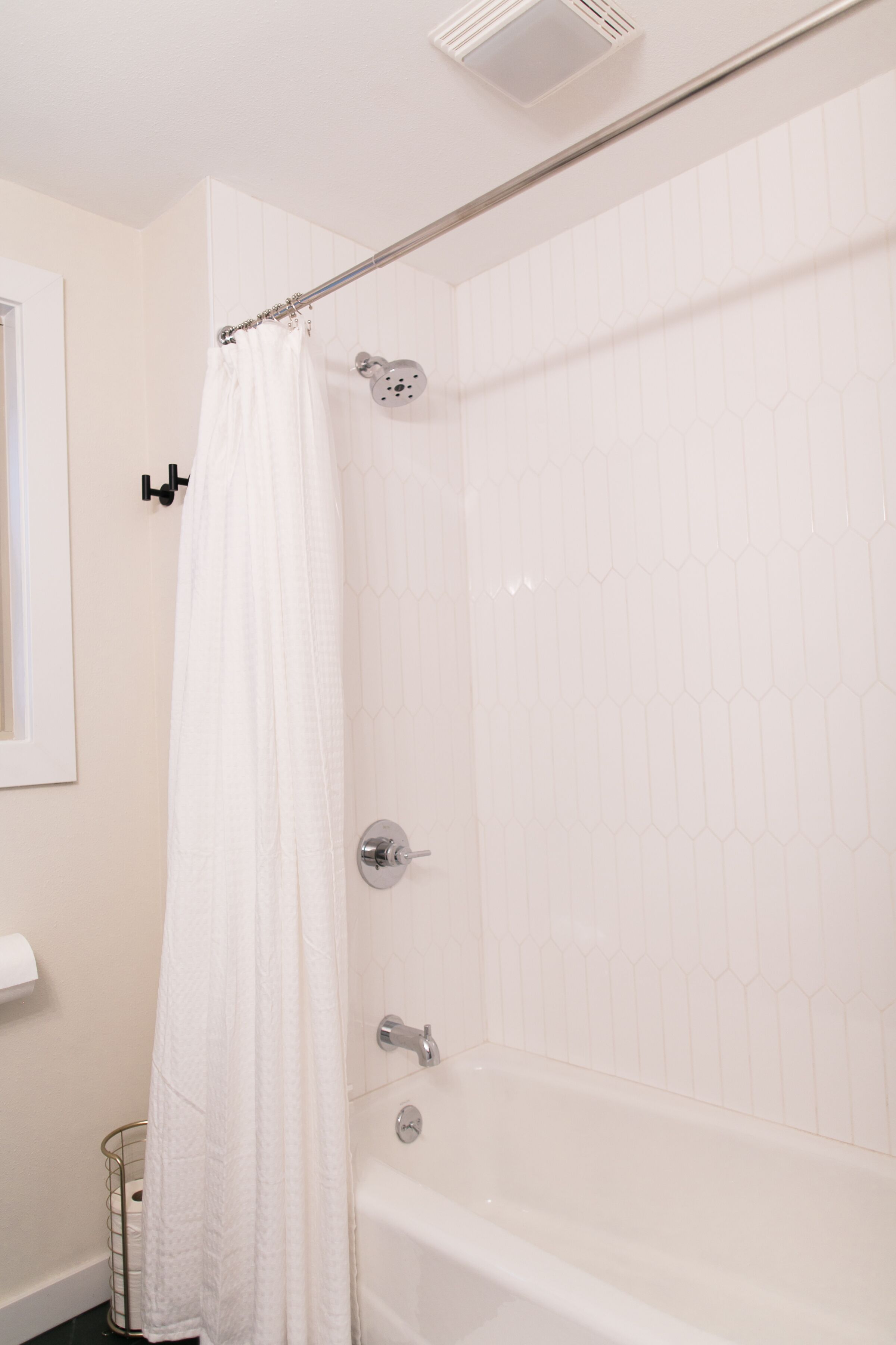 Un baño con una bañera blanca, una cortina de ducha y un dispensador de papel higiénico.