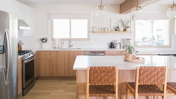 A modern kitchen with wooden cabinets, a stainless steel refrigerator, a built-in oven, and a large island with two chairs. - Beautiful Modern Home - Heated Indoor Pool (Spokane)