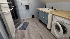 A compact kitchen with a washing machine, a sink, and a towel rack. - LA GRANGE DE MELLERAY (Outarville)