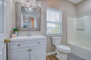 Une salle de bain avec un meuble-lavabo blanc, des toilettes et une douche à parois de verre.