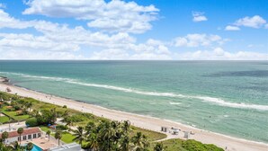 Une vue côtière comprenant une plage, l’océan et une zone résidentielle avec des maisons et une piscine.