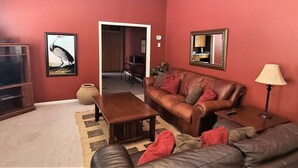 A living room with a brown leather sofa, a wooden coffee table, and a red wall. - The Westchester 1 BR located On The Bricks (Fairbury)
