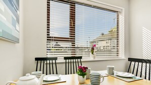 Un coin repas avec une table en bois, des assiettes blanches, une théière blanche et des chaises noires.