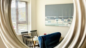 Un coin repas avec une table, des chaises et une vue sur les bateaux par la fenêtre.