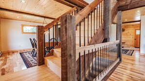 Un escalier en bois avec une rampe métallique menant à un deuxième étage.