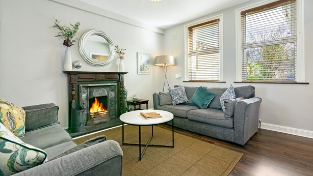 Ein Wohnzimmer mit Kamin, einer Couch, einem Couchtisch und einer Lampe.