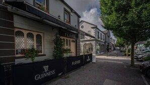 Straßenansicht eines Gebäudes mit einem Schild für 'Floods Bar' und dem 'Guinness'-Logo an der Fassade.