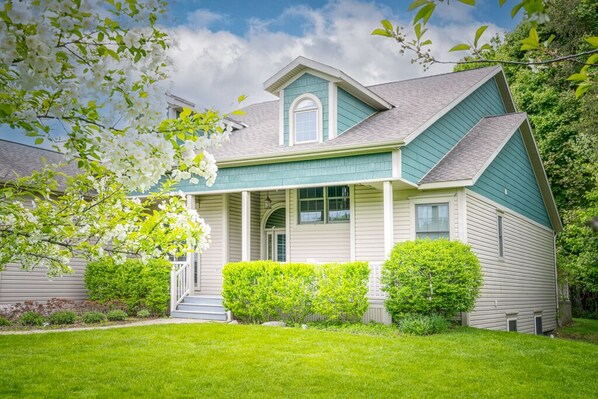 A two-story house with a front porch, a small front yard, and a garage.