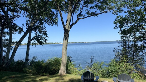 Dos sillas Adirondack mirando un lago bajo un cielo despejado.